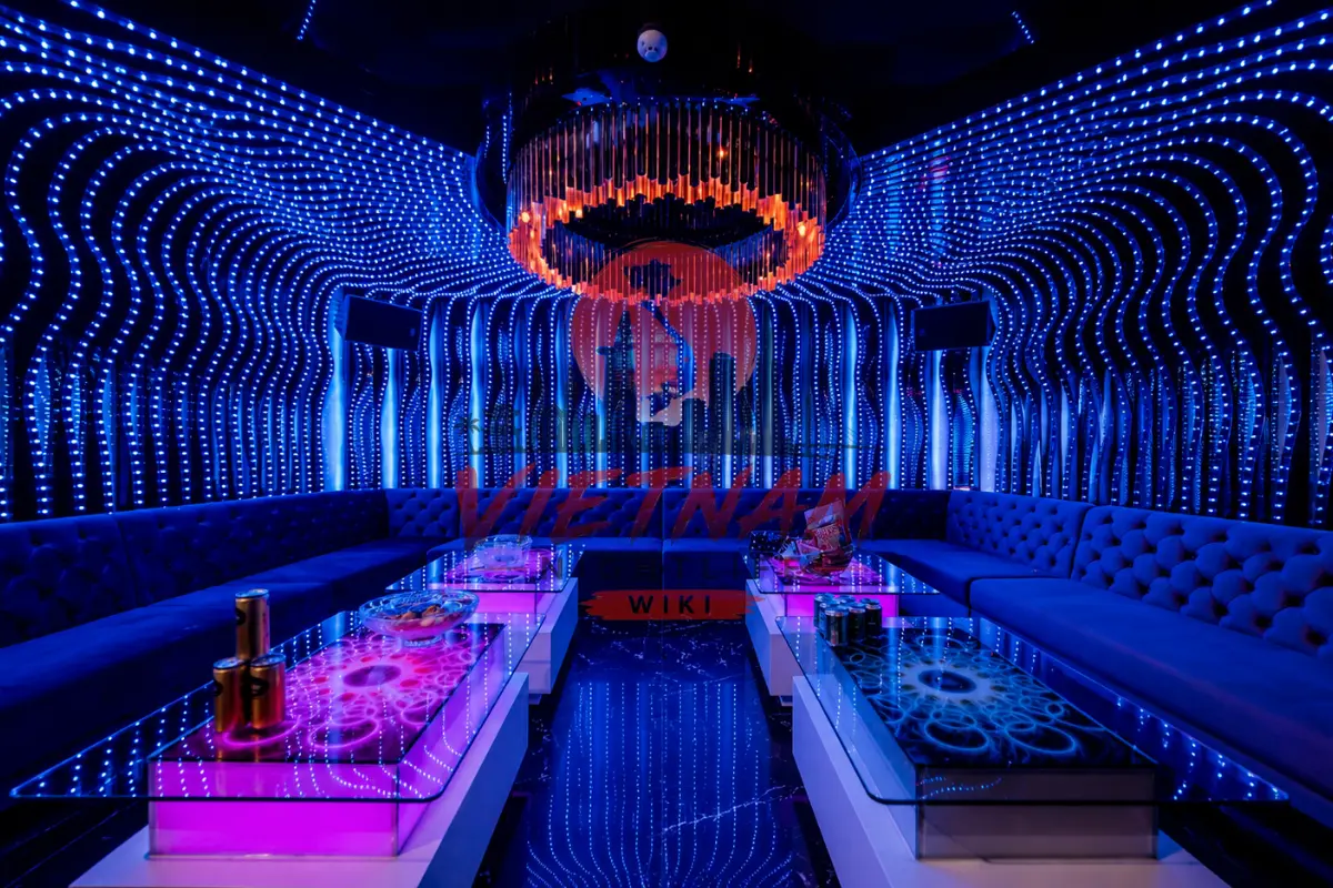 나트랑 퀸터 가라오케 도트 스트라이프 네온 LED 파티 룸 — 도트 스트라이프 미러 벽면과 오렌지 샹들리에 및 분홍빛 글로우 미러 테이블